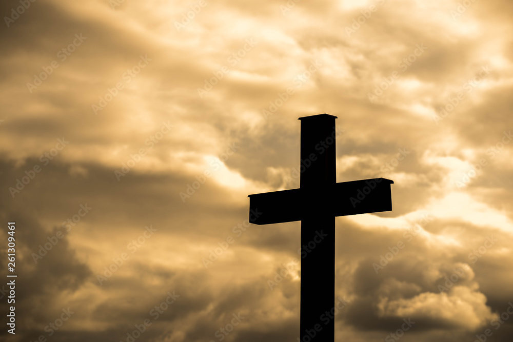 Simple wood catholic cross silhouette, dramatic orange storm clouds in the background, copy space.