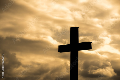 Simple wood catholic cross silhouette, dramatic orange storm clouds in the background, copy space.