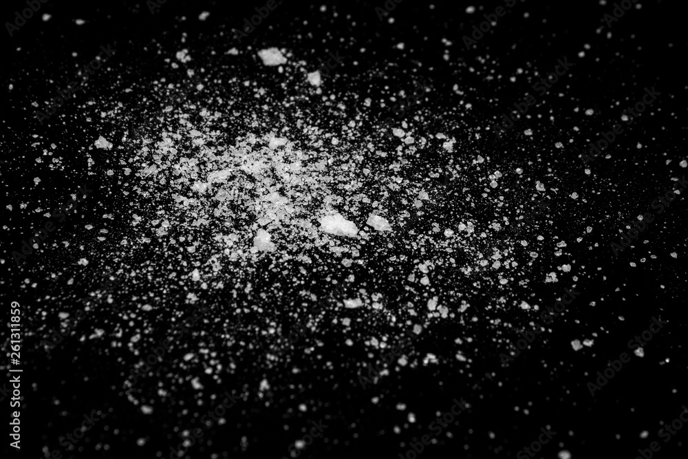white crystalline powder on a black background. sugar dust white crystalline powder on a black background. sugar dust