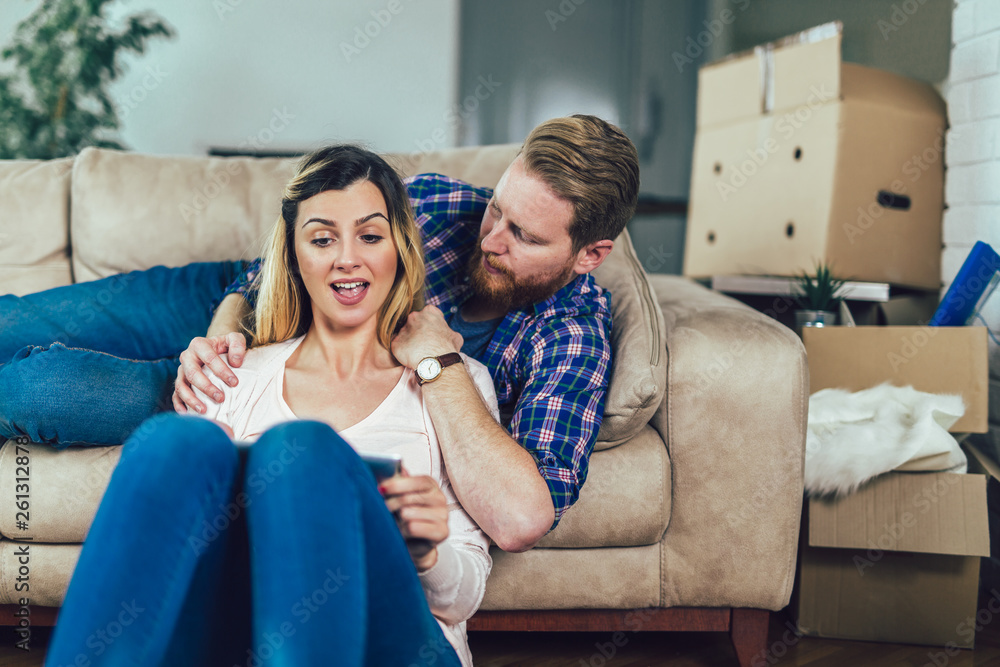 Obraz premium Couple in love sitting on the sofa and using tablet, having fun.