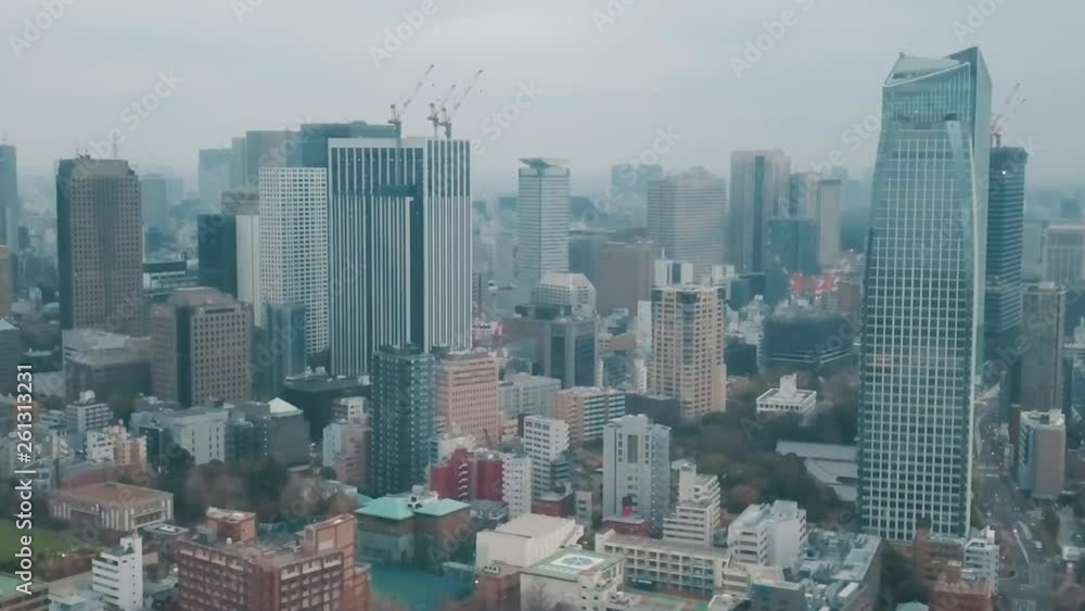 Aerial drone panning up towards the Tokyo city skyline in Japan on an overcast day with hazy smog filled skies and grey storm clouds above busy roads and skyscrapers Aerial drone panning up towards the Tokyo city skyline in Japan on an overcast day with hazy smog filled skies and grey storm clouds above busy roads and skyscrapers