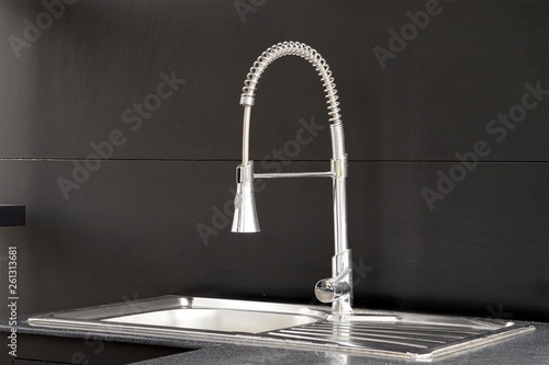 Modern kitchen faucet on black background.