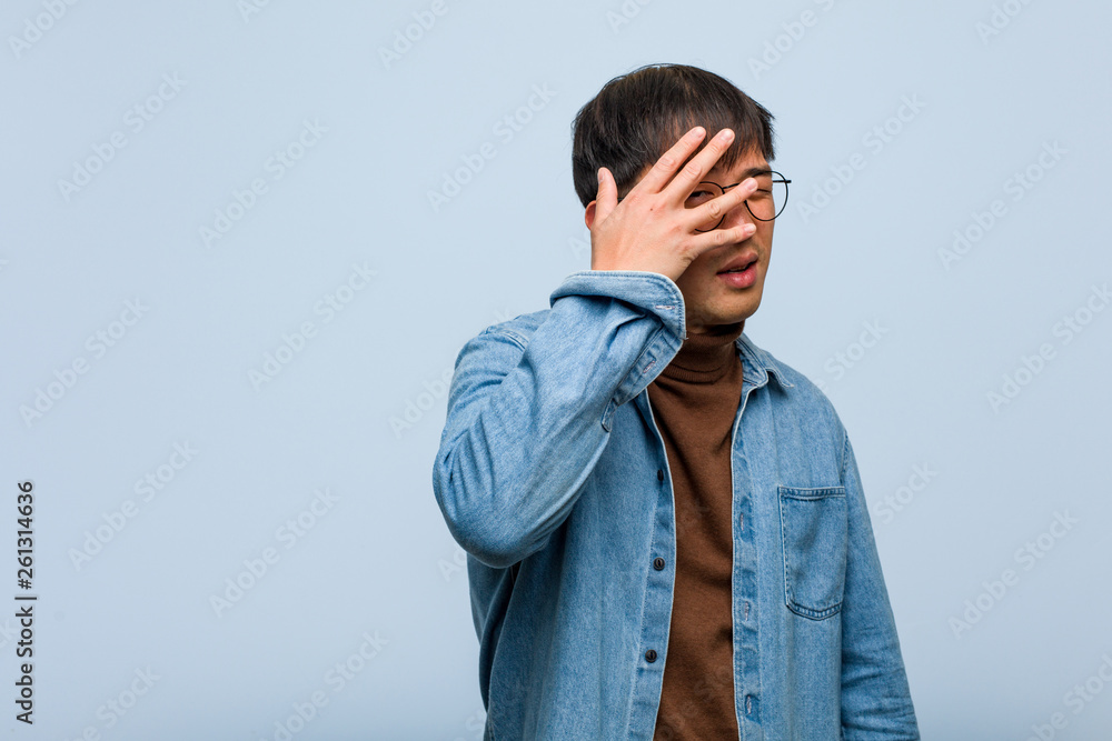 Young chinese man embarrassed and laughing at the same time Young chinese man embarrassed and laughing at the same time