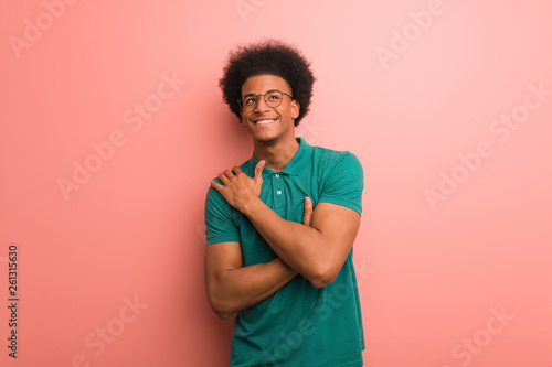 Valokuva Young african american man over a pink wall giving a hug