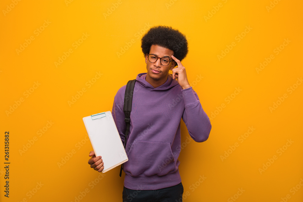 Young african american student man holding a clipboard thinking about an idea Young african american student man holding a clipboard thinking about an idea