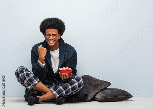 Young black man sitting and having a breakfast surprised and shocked © Asier
