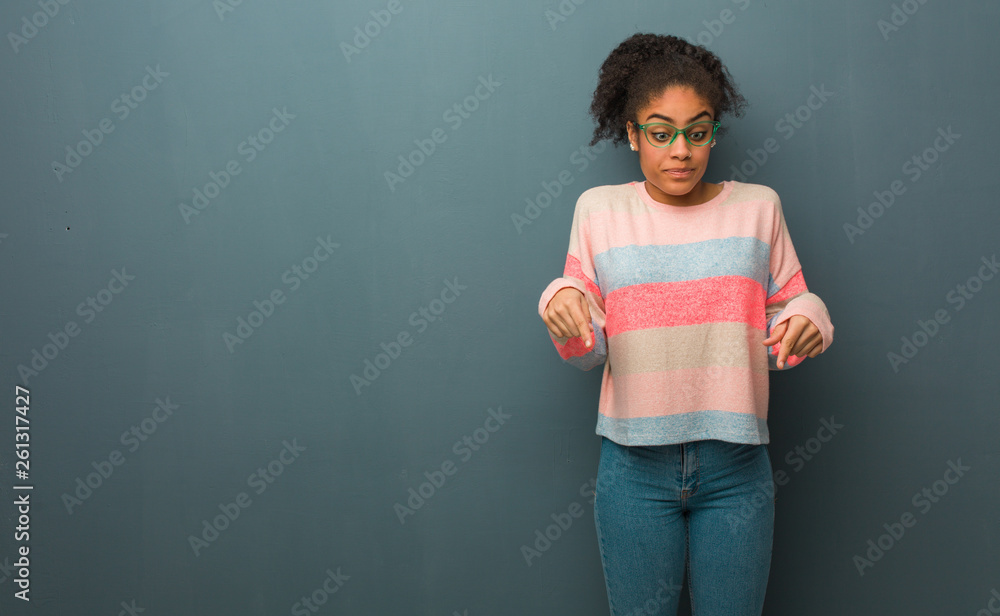 Fototapeta premium Young african american girl with blue eyes pointing down