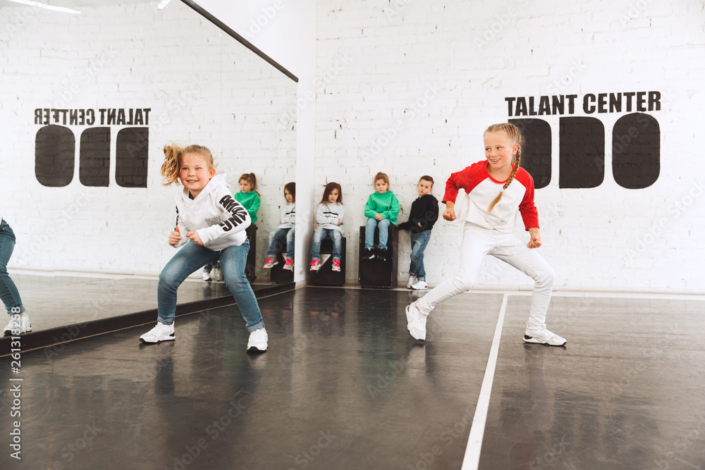 The kids at dance school. Ballet, hiphop, street, funky and modern dancers over studio background. Children showing aerobic element. Teens in hip hop style. Sport, fitness and lifestyle concept.
