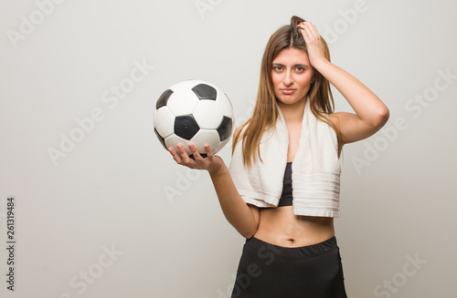Young fitness russian woman worried and overwhelmed. Holding a soccer ball. © Asier
