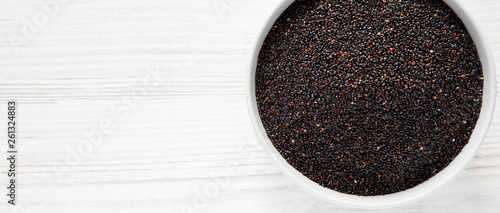 Gluten-free raw organic black quinoa in a bowl over white wooden background, top view. From above, overhead, flat lay. Copy space.