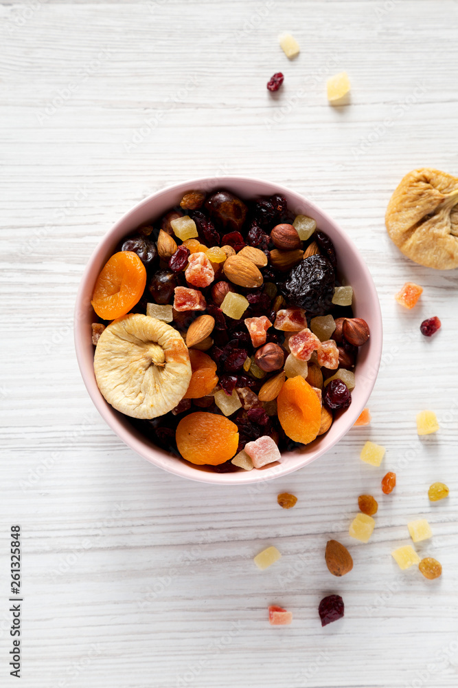 Dried fruits and nuts in a pink bowl over white wooden table. Top view, from above, flat lay. Close-up. Dried fruits and nuts in a pink bowl over white wooden table. Top view, from above, flat lay. Close-up.