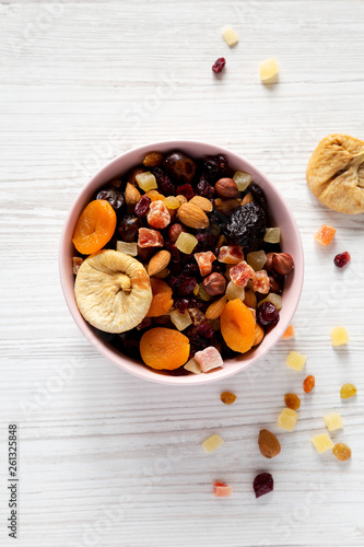 Dried fruits and nuts in a pink bowl over white wooden table. Top view, from above, flat lay. Close-up.