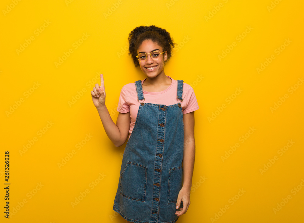 Young black african american girl with blue eyes showing number one Young black african american girl with blue eyes showing number one