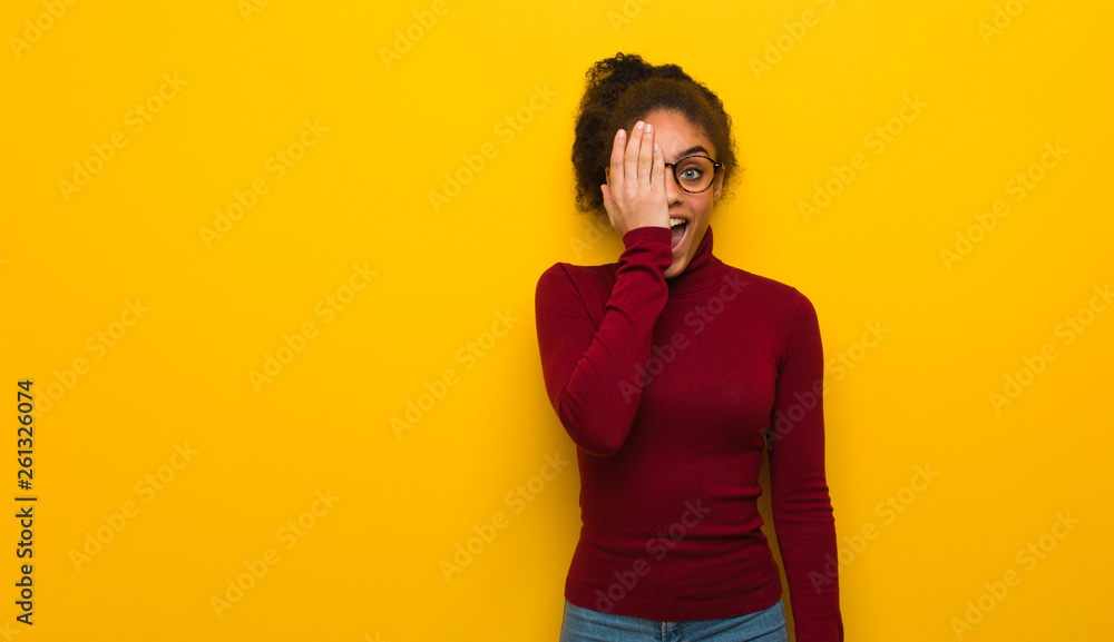 Young black african american girl with blue eyes shouting happy and covering face with hand Young black african american girl with blue eyes shouting happy and covering face with hand