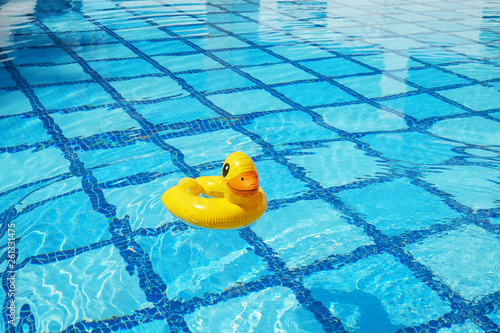 Fotomurale Top view of inflatable duck floating in an empty swimming pool with crystal clear water and blue square tile pattern background