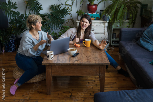 Friends looking at a laptop together at home