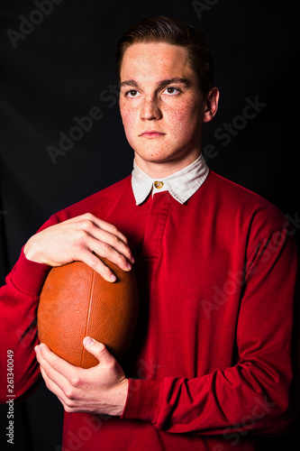 Redheaded man in red shirt holding ball for ragby photo