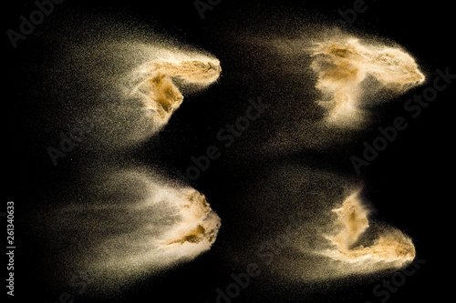 Four photos of sand explosion isolated on black background. Freeze motion of sandy dust splashing.