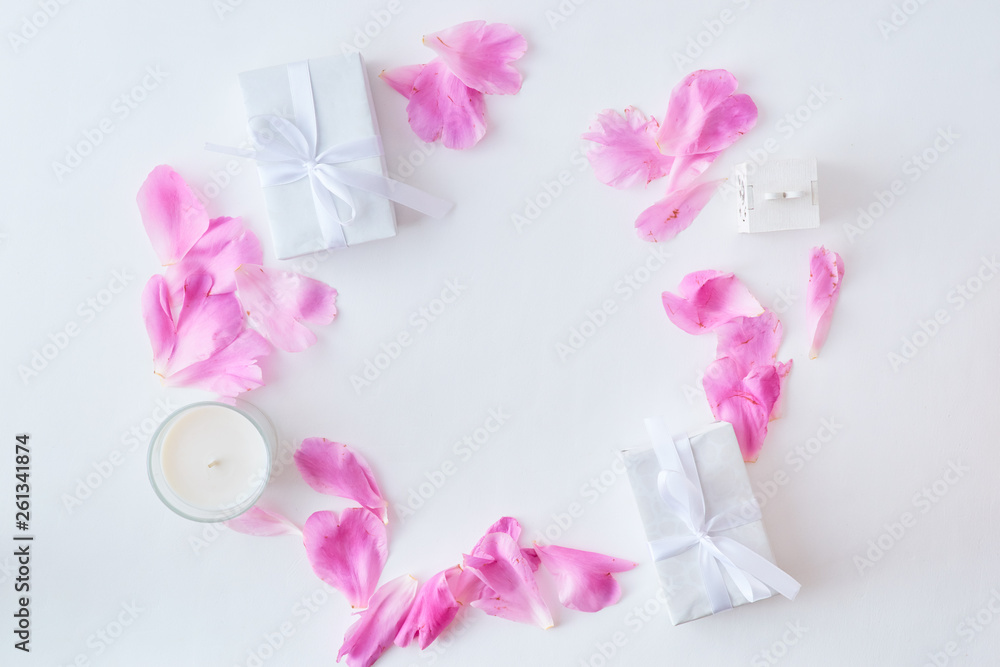 Flat lay composition with pink petals and gift box on a white background