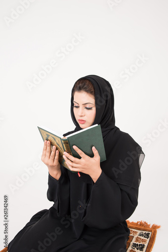 Arab muslim woman reading the holy Quran and praying