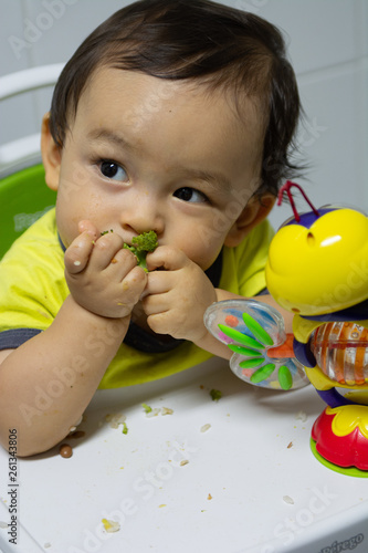 Baby boy eating happy broccoli