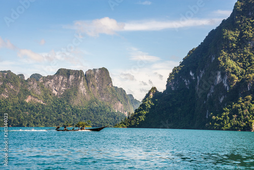 Longtail boat in lake. Beautiful nature rock mountains cliff and blue water color lake with blue clear sky in Ratchaprapa Dam at Khao Sok National Park, Surat Thani, Thailand. Asia tourism location.
