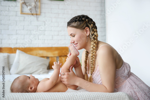 Loving young mother playing with her baby in bedroom
