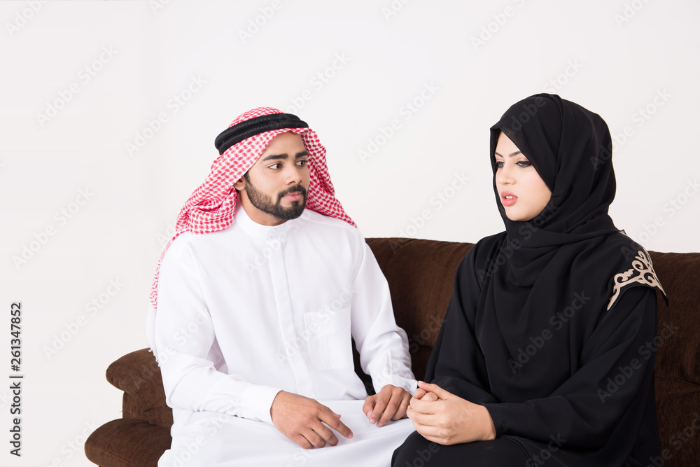Arab couple fighting and discussing family issues while sitting on sofa chair at home