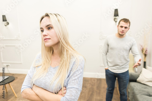 Unhappy young couple quarreling in the living room.