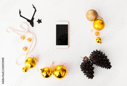 Top view on nice Christmas gift wrapped in white gift paper, Christmas tree decorations on white wooden background with sparkling stars. New Year, hol