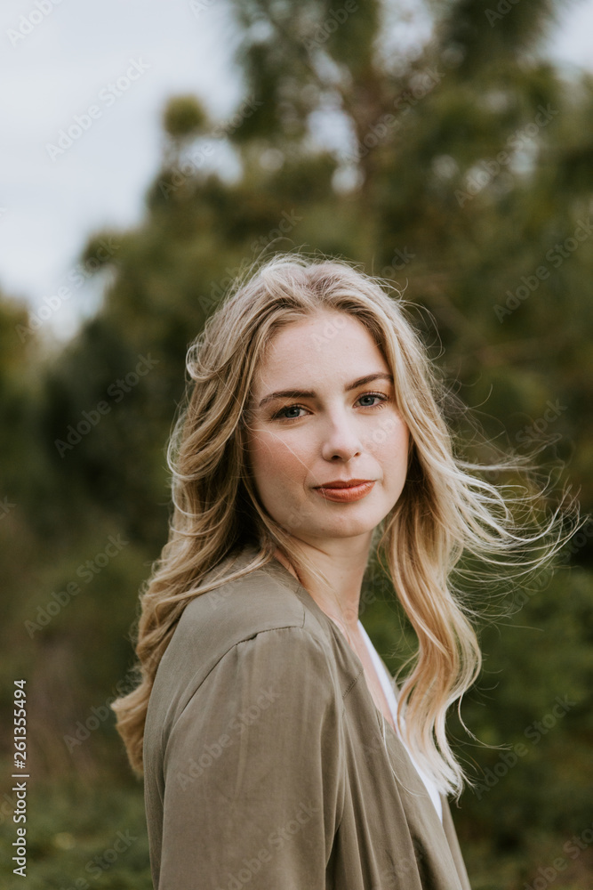 Naklejka premium Pretty Young Beauty Woman Model with Gorgeous Long Blond Hair Blowing in the Wind Smiling for Portrait Shots Outside at the Park