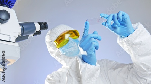 Scientist looks at a medical glass slide with bacteria through light. photo