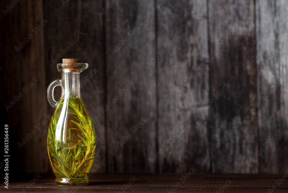 Bottles of olive oil with thyme and rosemary on a dark background. Copy space.