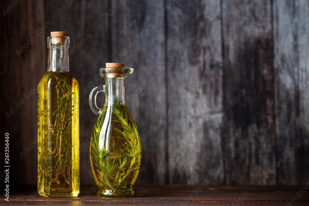 Olive oil with herbs in transparent bottles on a dark background. Rustic. Copy space. Olive oil with herbs in transparent bottles on a dark background. Rustic. Copy space.