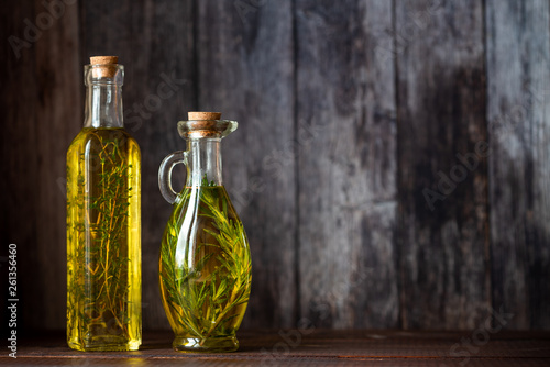Olive oil with herbs in transparent bottles on a dark background. Rustic. Copy space.