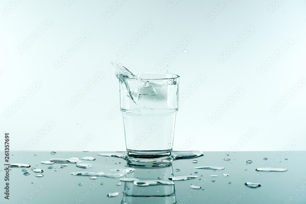 Glass of pure fresh water with ice cube.Reflection of crystal glass from the table on white background. Concept of Nature, Healthy Lifestyle. Healthcare And Beauty, freshness.