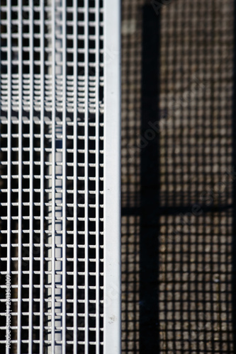 Die Nahaufnahme und Draufsicht auf die Sitzfläche einer Gitterbank, welche Schatten wirft. . © ginton