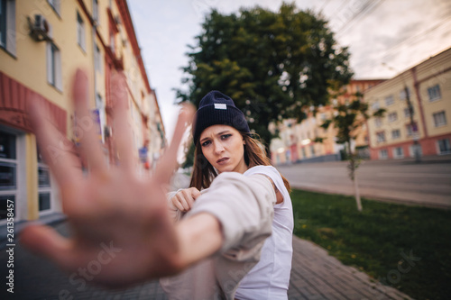 The girl shows a refusal. Girl in stylish clothes and hat.