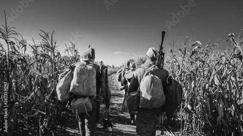 Group Of Re-enactors Dressed As World War II Russian Soviet Red Army Soldiers Marching Through Autumn Cornfield. Photo In Black And White Colors. Soldier Of WWII WW2 Times