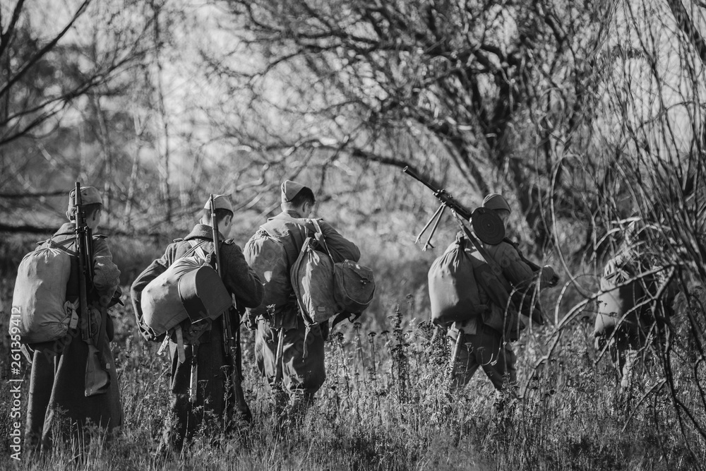 Re-enactors Dressed As World War II Russian Soviet Red Army Soldiers Marching Through Forest In Autumn Day. Photo In Black And White Colors. Soldier Of WWII WW2 Times