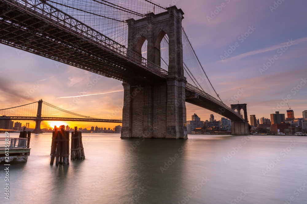 Fototapeta premium Brooklyn Bridge o wschodzie słońca z East River z długim naświetleniem zdjęciem
