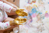 Kind mit goldener Fingerbarbe auf Hand. Kid with golden finger paint on hand.