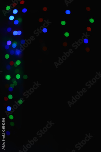 Colored lights (garland) in the dark. Bokeh effect Festive illumination.