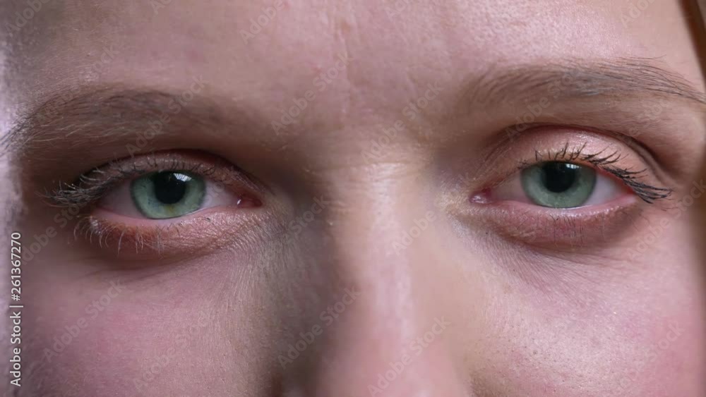 Eye-portrait of young blonde straight-haired woman watching calmly and intently into camera on black background. Eye-portrait of young blonde straight-haired woman watching calmly and intently into camera on black background.