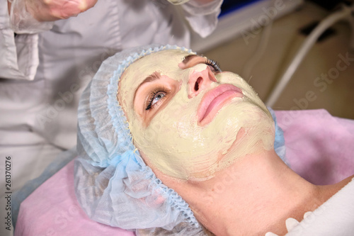 Cosmetologist making a face mask to her patient  . Anti-ageing and smoothing procedure in a beauty salon. Doctor in a cosmetological clinic making a treatment of skin care