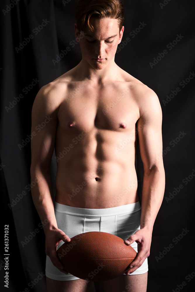 Rugby player with ball isolated on black in studio