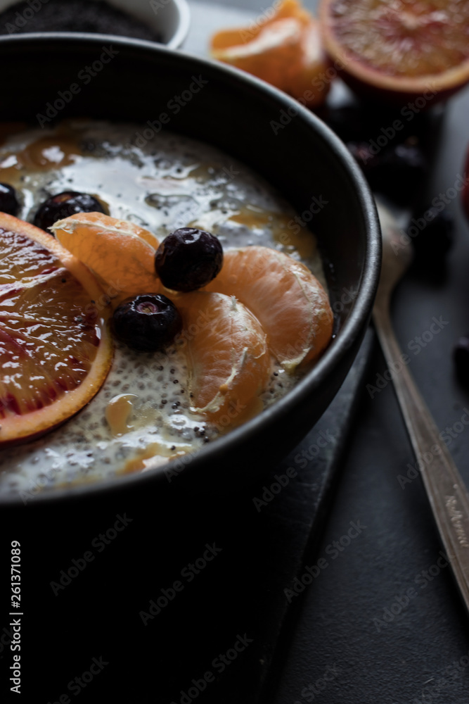 From above chia seeds pudding with slices of orange, mandarins and olives in bowl near spoon and grapefruit on dark table From above chia seeds pudding with slices of orange, mandarins and olives in bowl near spoon and grapefruit on dark table