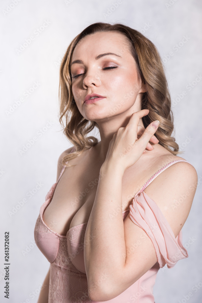 Portrait of beautiful young elegant female in pale pink wedding dress with big neckline, on a white background.