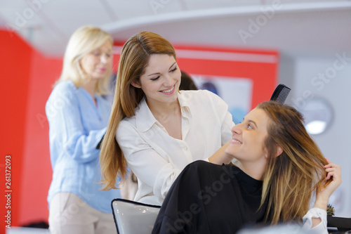 happy woman in hairdressing talking to hairdresser