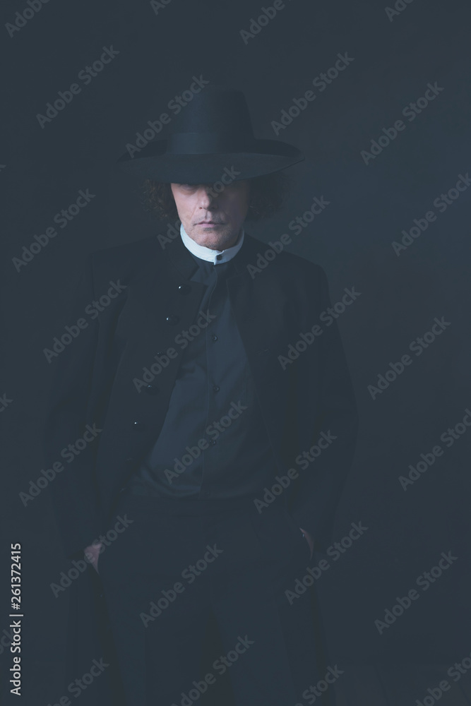Mysterious victorian man in hat and black coat.